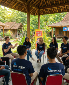 Suasana belajar speaking bahasa Inggris yang seru dan interaktif di lembaga kursus Interpeace Kampung Inggris Pare, dengan para siswa mengenakan kaos seragam 'Jago Speaking' di bawah gazebo pedesaan yang asri.